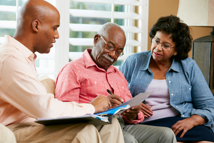 A man sits on a couch with an older woman and man, discussing a nursing care facility in GreenAcres Place in Bossier City, LA